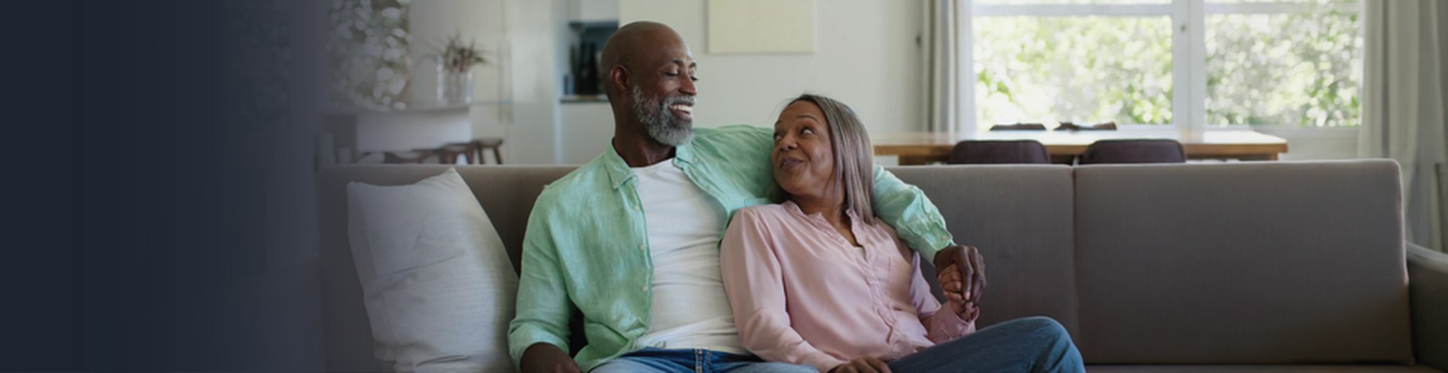 Photo of a retired couple smiling on a porch at sunset
