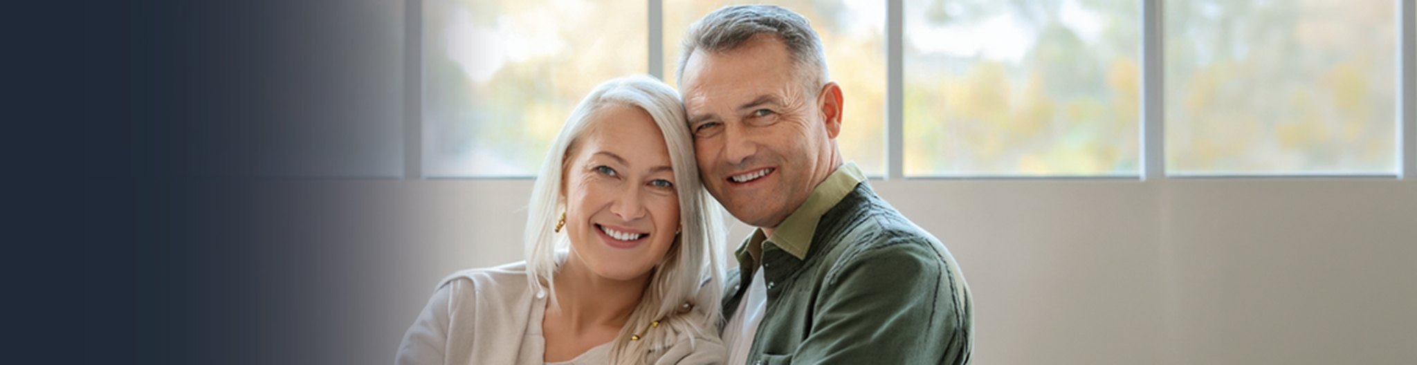 Photo of a retired couple smiling on a porch at sunset
